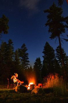 two people sitting around a campfire at night