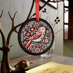 a christmas ornament hanging from a tree on a table next to a note