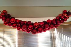 red ornaments are hanging on the window sill in front of blinds with white blinds