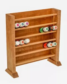 a wooden shelf with several different colored bottles on it's sides and two shelves holding pens