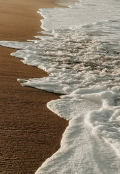 the waves are coming in to the beach and it is very dark brown with white foam