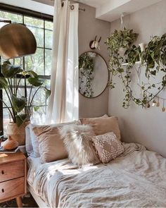 a bed sitting under a window next to a wooden dresser and potted plant on top of it