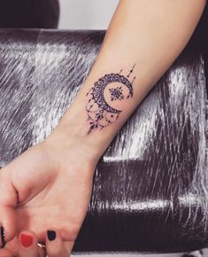 a woman's arm with a small tattoo on the wrist and an intricate design