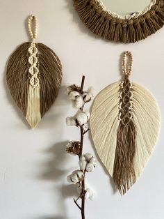 two pieces of art hanging on the wall next to a mirror and cotton plant with dried flowers