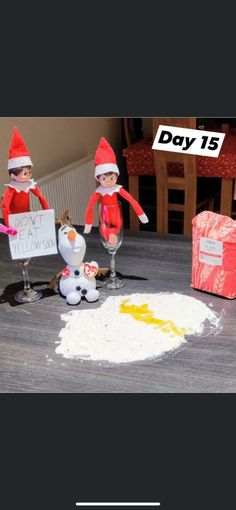 two elfs are making snowmen out of doughnut holes on the floor and one is holding a sign that says day 13