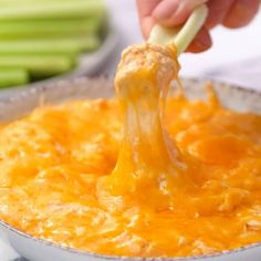 a person is dipping cheese into a casserole dish