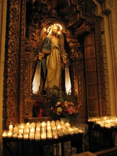 the statue is surrounded by candles and flowers