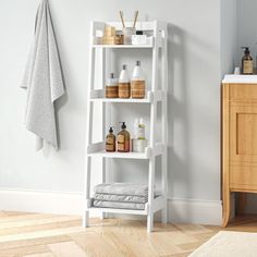 a white shelf with bottles and soaps on it next to a sink in a bathroom