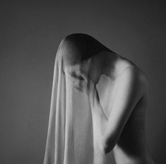 black and white photograph of a naked woman covering her face with a veil over her head