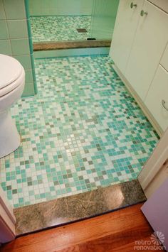 a bathroom with green and white tiles on the floor