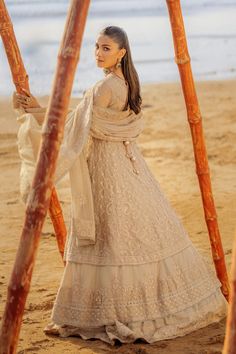 a woman standing on top of a sandy beach next to the ocean wearing a white dress