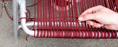 a person is holding onto a red and white bench that's attached to a metal pole