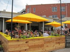 people sitting at tables under yellow umbrellas outside