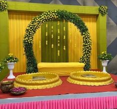 a decorated stage set up with flowers and greenery on the top, surrounded by vases