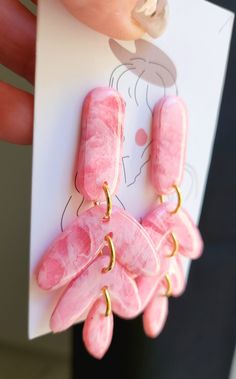 a pair of pink earrings is being held up