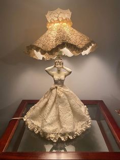 a lamp that is sitting on top of a glass table in front of a woman's dress