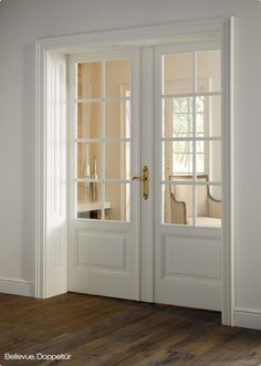 an empty room with two white doors and wood flooring in front of the door