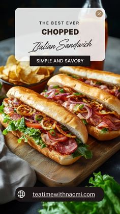 two sub sandwiches on a cutting board with chips and ketchup in the background