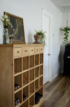 a wooden cabinet with shoes and plants on top