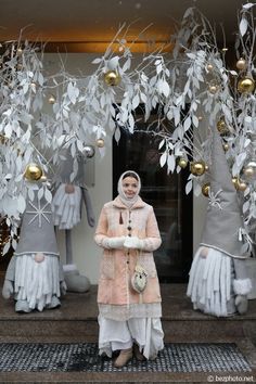 a woman standing in front of some christmas decorations