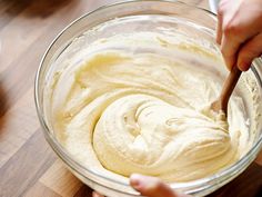 someone mixing batter in a glass bowl on top of a wooden table