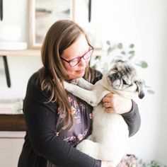 a woman holding a pug dog in her arms