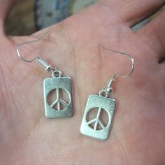 "Peace Sign Earrings These are small flat rectangular \"dog tag\" type charms with a peace sign -- very low key -- The charms are .75\"h x .5\"w\" -- I made them using new silver tone hypo allergenic ear wires that you would normally find at a jewelry store or hobby shop. Please check out our store for other cool stuff...thanks for looking and enjoy your experience!!" Key Symbol, Peace Sign Jewelry, Peace Sign Earrings, Moon Bracelet, Indie Jewelry, Hippie Earrings, Hippie Necklace, Small Flat, Girl Jewelry