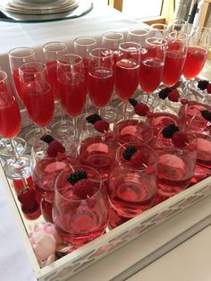 a tray filled with wine glasses and raspberries