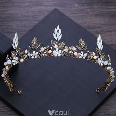 a tiara with flowers and leaves on top of a black box next to a pair of scissors