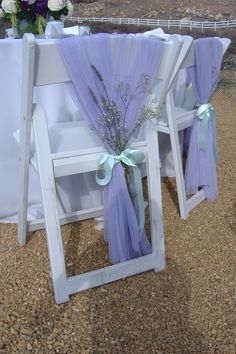 two white folding chairs with purple sashes and flowers on the back set up for a wedding ceremony