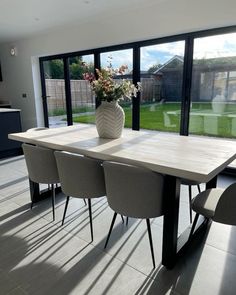 a dining room table with chairs and a vase filled with flowers