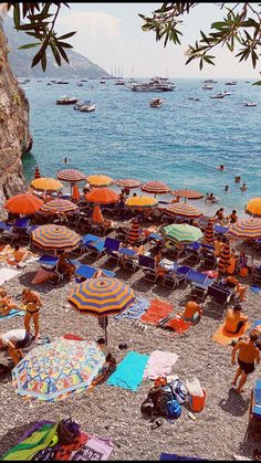 many people are on the beach with umbrellas and chairs in front of the water