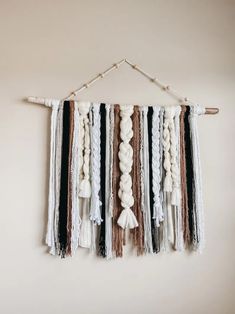 the wall hanging is decorated with white, black and brown tassels