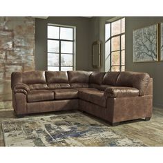 a large brown sectional couch sitting on top of a rug in front of a window