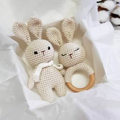 two crocheted rabbits sitting next to each other in a white box with cotton