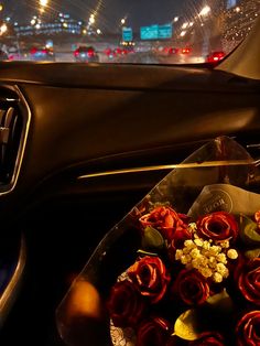 a bunch of red roses sitting in the passenger seat of a car at night time