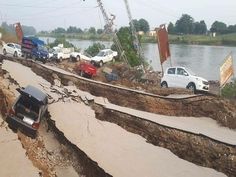 cars are parked on the side of a road that has been badly damaged by an overpass