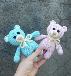 two crocheted teddy bears are being held by someone's hand