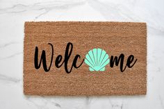 a welcome mat with the word welcome written in black on it and a yellow shell