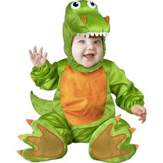 a baby in a dinosaur costume sitting on the ground with his hands up and mouth wide open