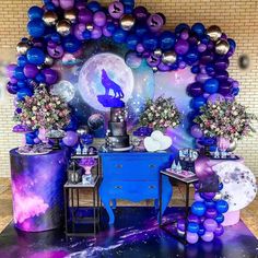 a purple and blue space themed party with balloons on the wall, tables and chairs