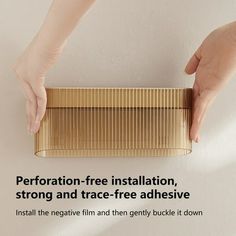 a person holding a golden box with the text,'free installation, strong and trace - free adhesivee install the negative film and then gently buckle it down