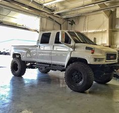 a white truck parked in a garage with no doors on it's sides and two large tires