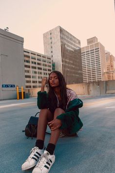 a woman sitting on the ground in front of some buildings