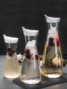 three vases with flowers and berries in them sitting on a counter top next to ice