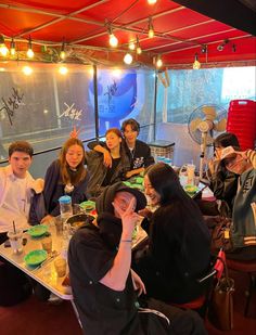 a group of people sitting around a table with food and drinks in front of them