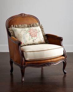 an old chair with a pillow on top of it sitting in front of a white wall