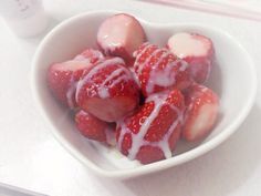 some strawberries are in a white bowl with yogurt drizzled on them