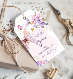 a thank you tag with flowers and butterflies on it sitting next to some crafting supplies