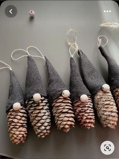 several cones are lined up on a table with string and pinecones attached to them